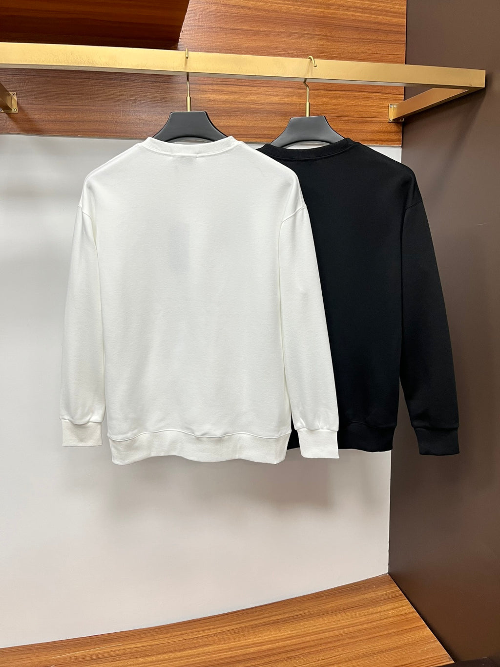 Back view of white and black crewneck sweatshirts on hangers