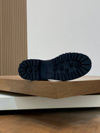 Outsole view of dark high-top boots with ridged tread and molded traction pattern