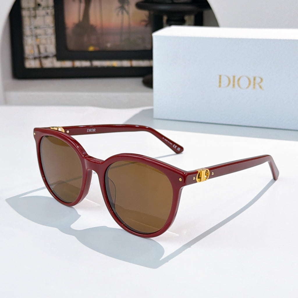 Sunglasses with red frames and amber gradient lenses, gold logo detail on temple