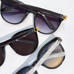 Sunglasses close-up with black frames and dark lenses, gold hinge details visible