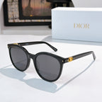 Sunglasses with black frames and gray gradient lenses, gold hinge detail on temple