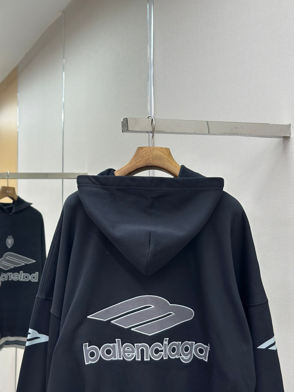 Balenciaga navy pullover hoodie back view with large logo graphic on hanger