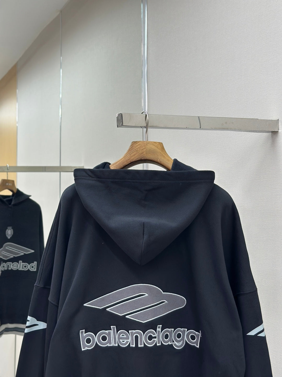 Balenciaga navy pullover hoodie back view with large logo graphic on hanger