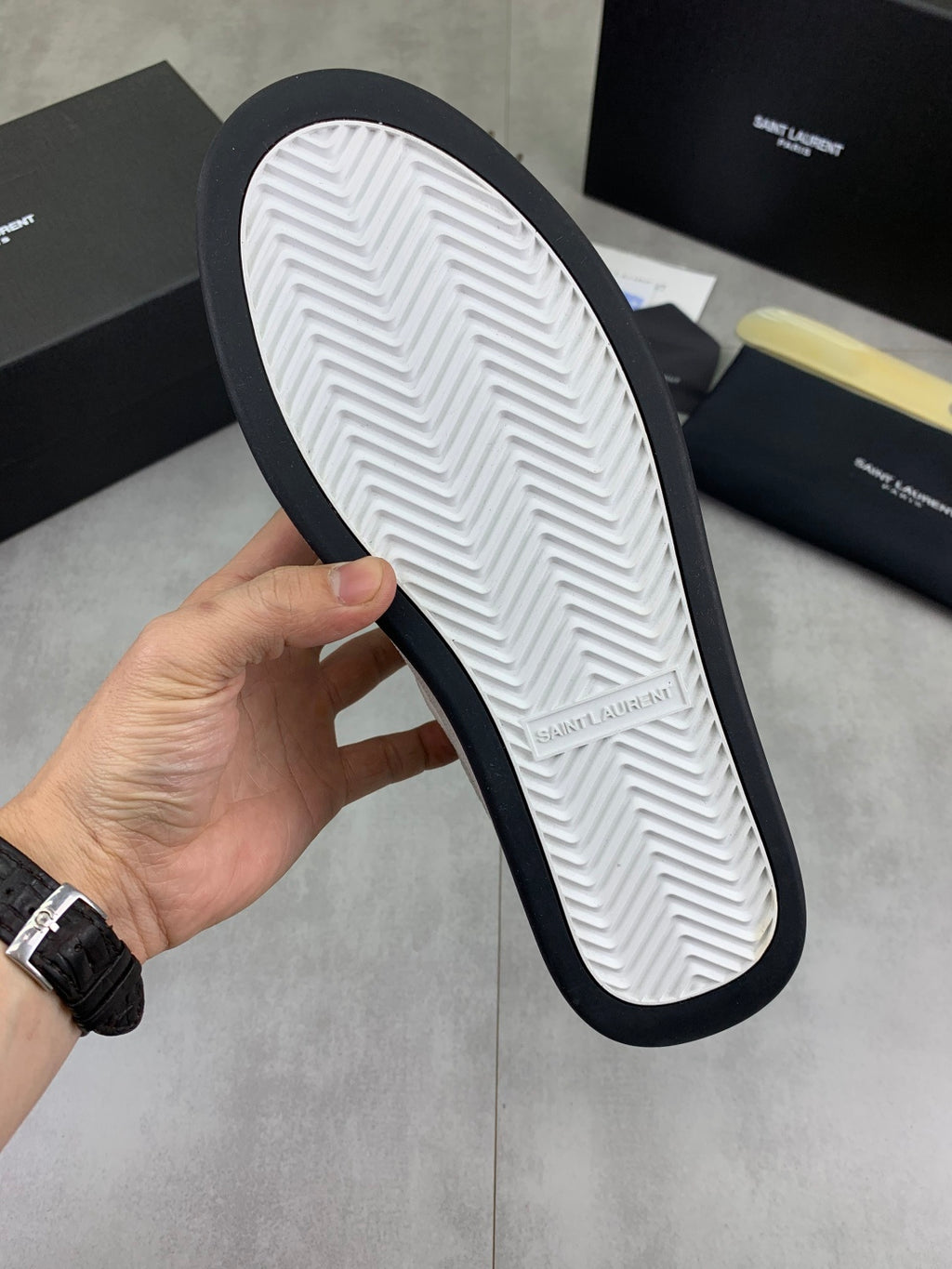 Sole of white low-top sneaker showing chevron tread and navy outer edge