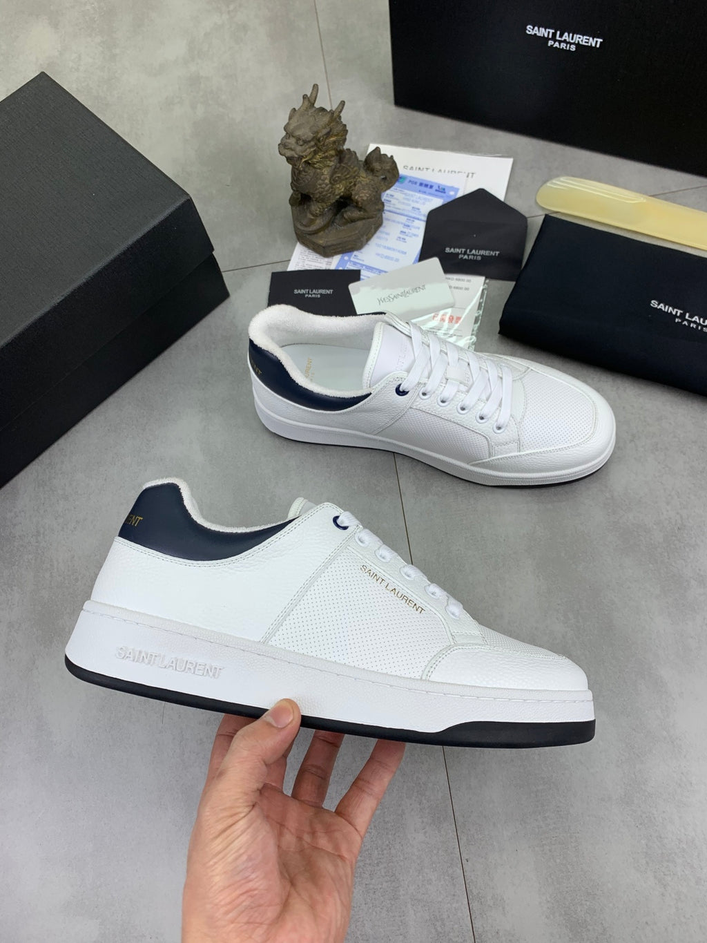 White low-top sneakers with navy-trimmed collar and black side logo