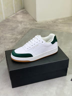 White low-top sneakers with green suede accents and gum sole