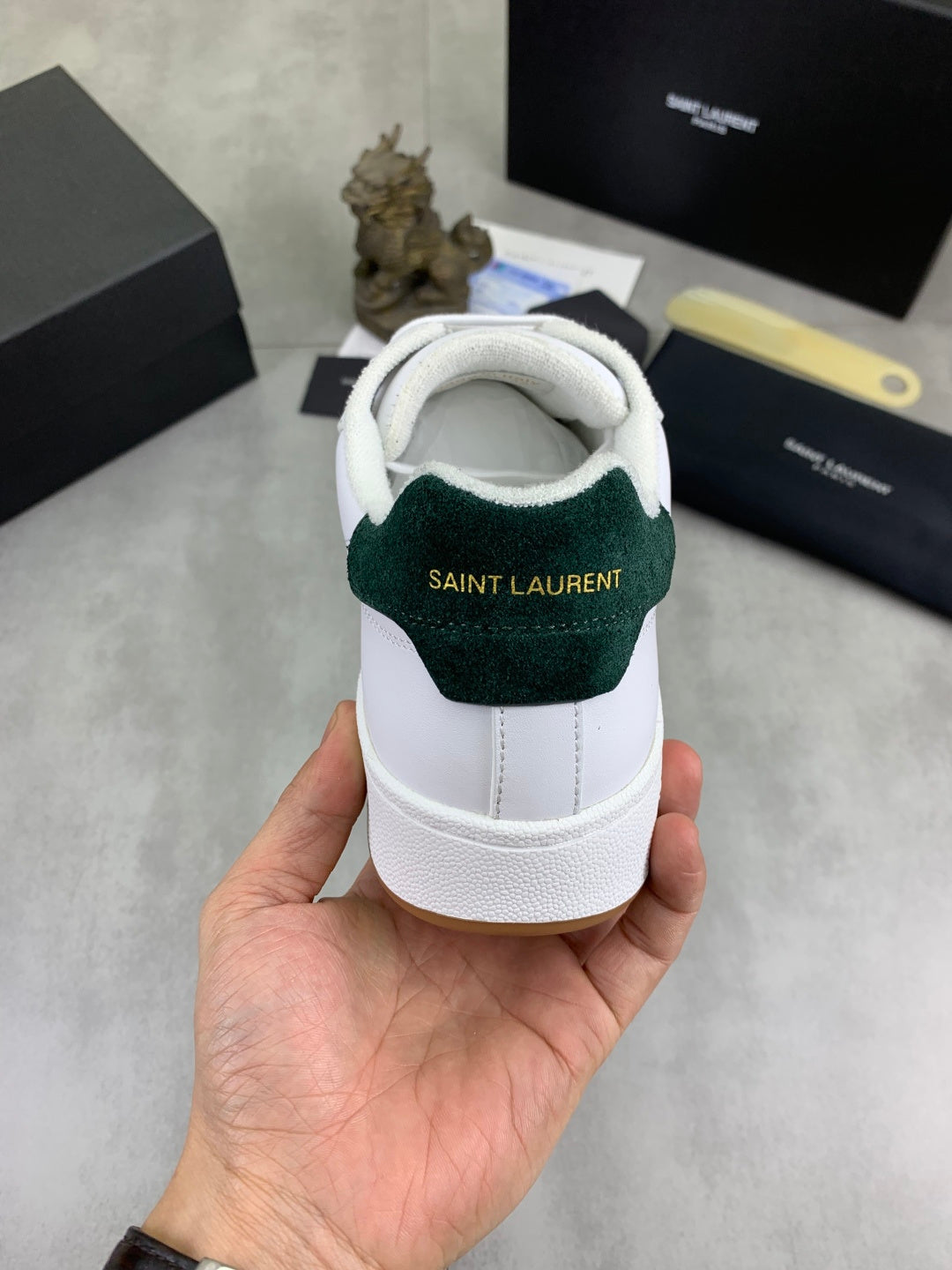 Back view of white sneakers with green heel panel and SAINT LAURENT lettering