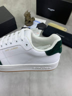 White leather sneakers with green suede collar trim and lace-up front