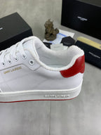 White sneaker with red heel patch, cushioned collar, and lace-up front.