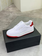 White low-top sneaker with red outsole edge and white lace-up front.