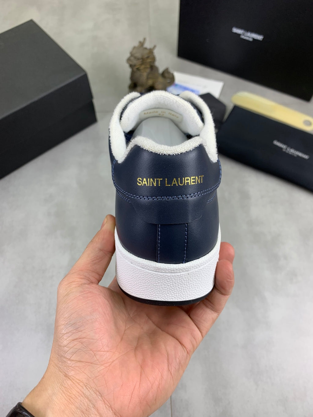 Back of navy sneakers with white heel panel and padded collar, SAINT LAURENT text