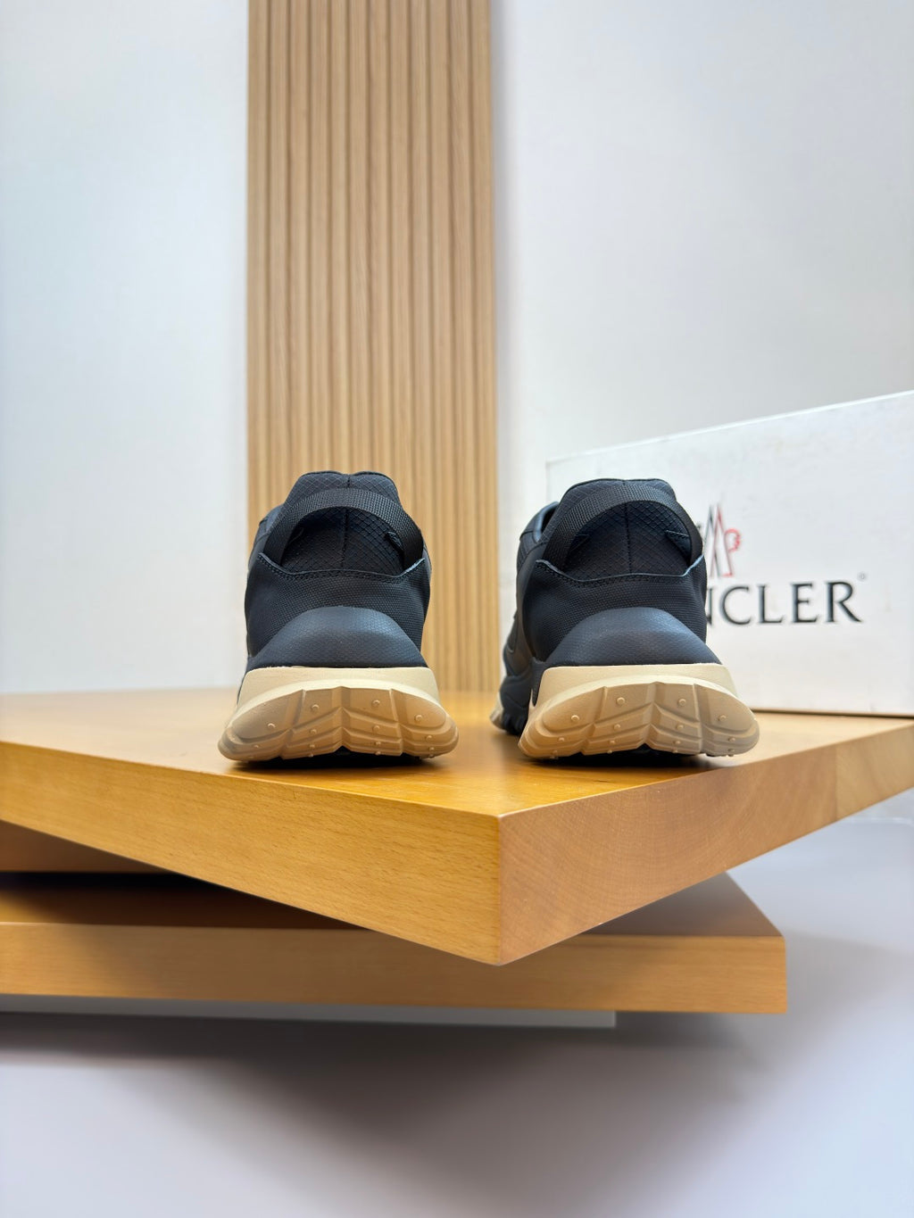 Moncler sneakers rear view on shelf, dark navy with gum yellow sole and heel panels