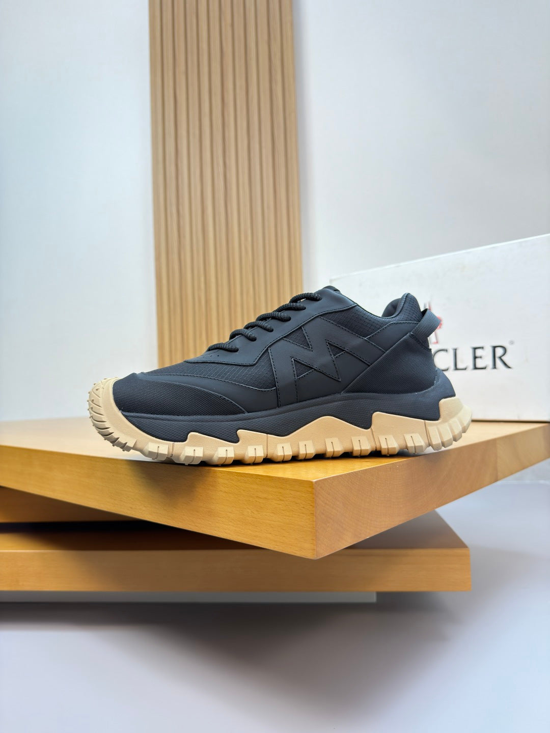 Moncler lace-up sneakers on display shelf, dark navy upper with gum yellow outsole