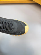 Moncler sneaker close-up of toe and side: dark navy upper with gum yellow trim