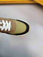 Close-up of sneaker toe and laces; olive leather with black trim and white laces.