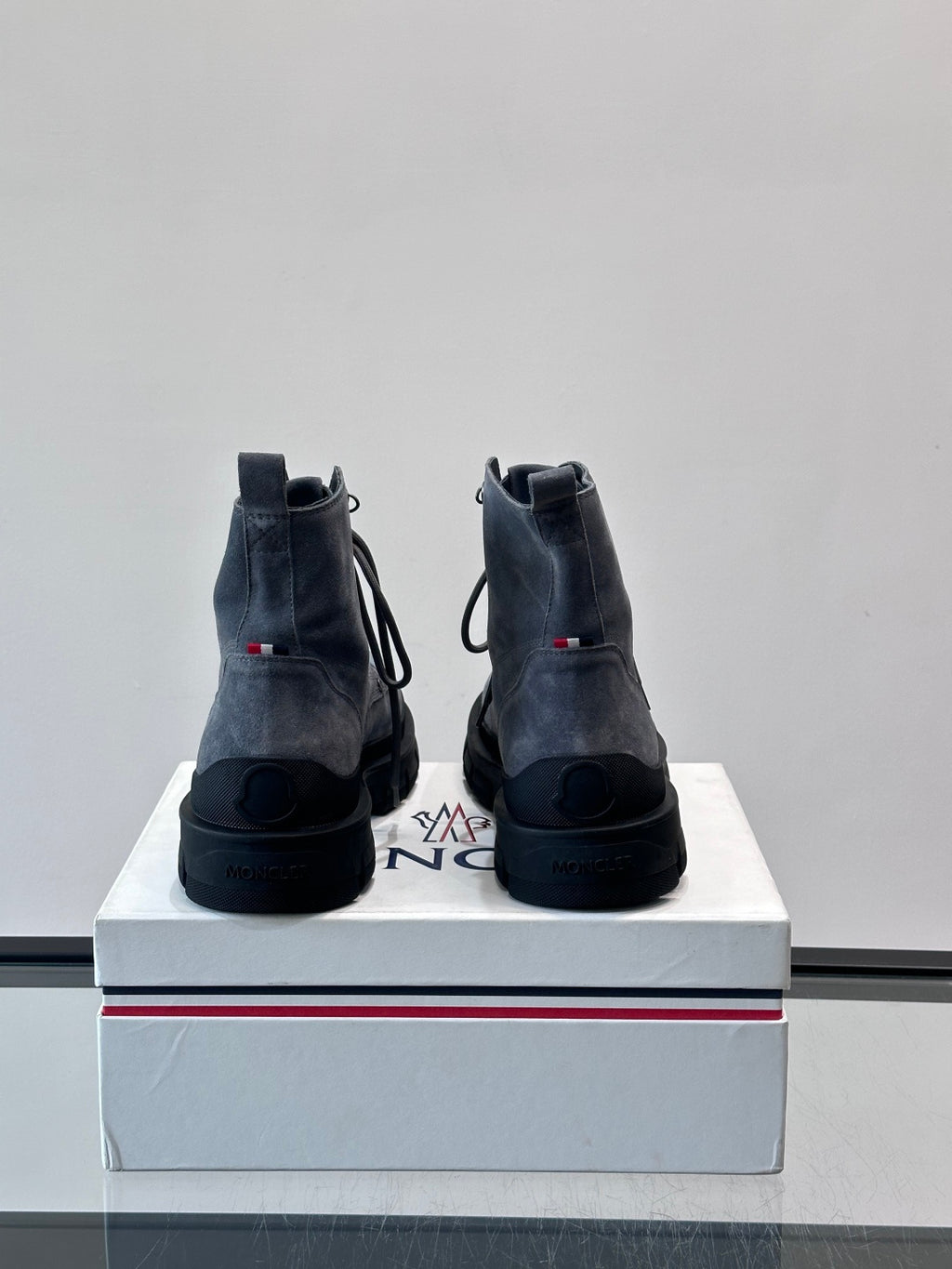 Moncler boots rear view on box; dark blue suede, lace-up style, rugged tread outsole