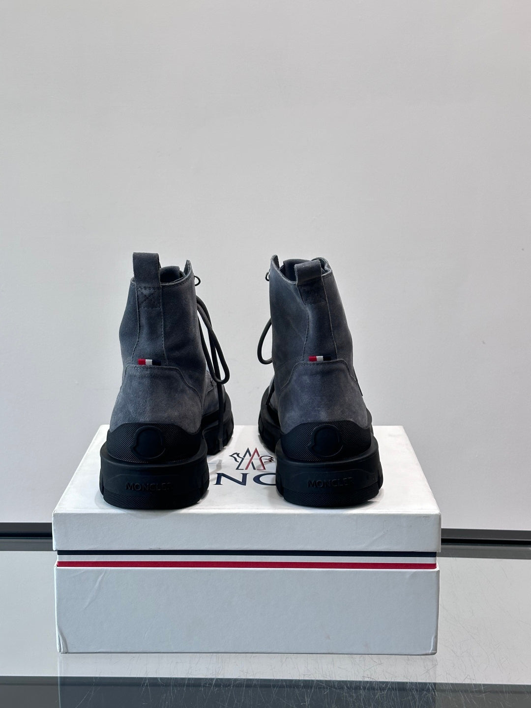 Moncler boots rear view on box; dark blue suede, lace-up style, rugged tread outsole