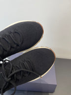 Close-up of black knit sneaker toe with laces and rubber sole edge