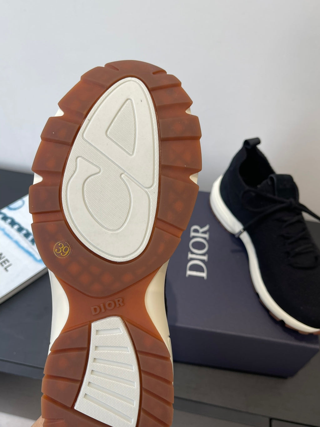 Sneaker outsole view with white tread and Dior logo on gum rubber