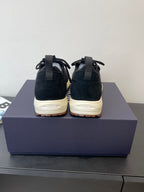 Pair of black lace-up sneakers with ankle pull tab and cream soles