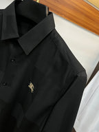 Long-sleeve button-up shirt in dark black with logo on the chest and fold-over collar