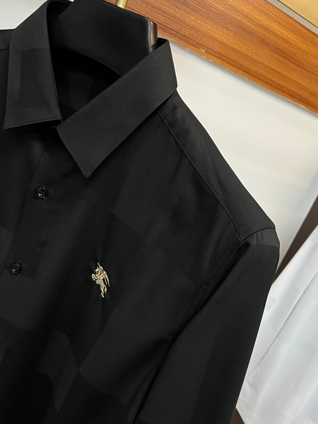 Long-sleeve button-up shirt in dark black with logo on the chest and fold-over collar