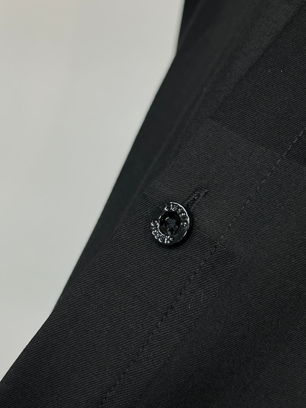 Dark black shirt cuff with round button and stitched detail