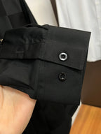 Dark black shirt cuff with two buttons and round emblem detail