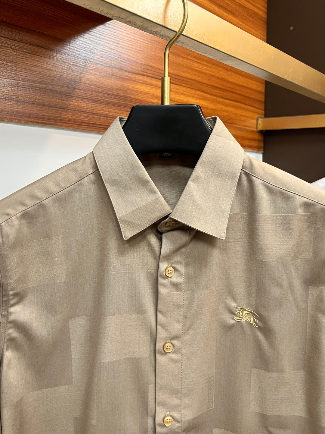 Beige button-up shirt collar with front buttons and small embroidered crest