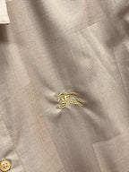 Beige shirt fabric with small gold embroidered crest at the chest