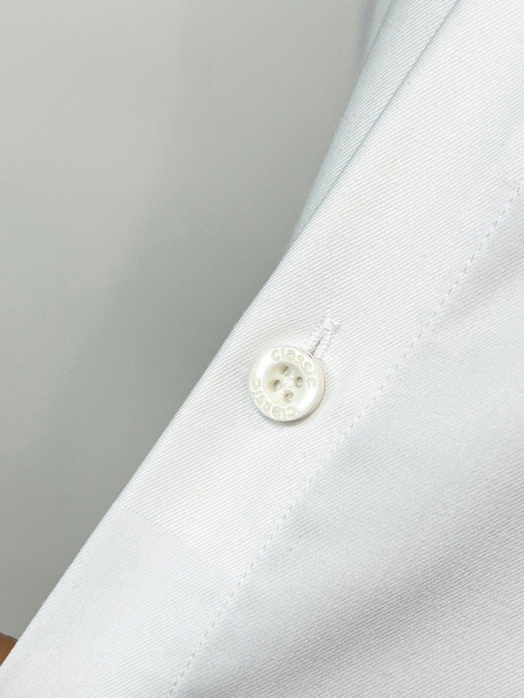 Burberry long-sleeve shirt cuff with white button and stitched placket on white fabric