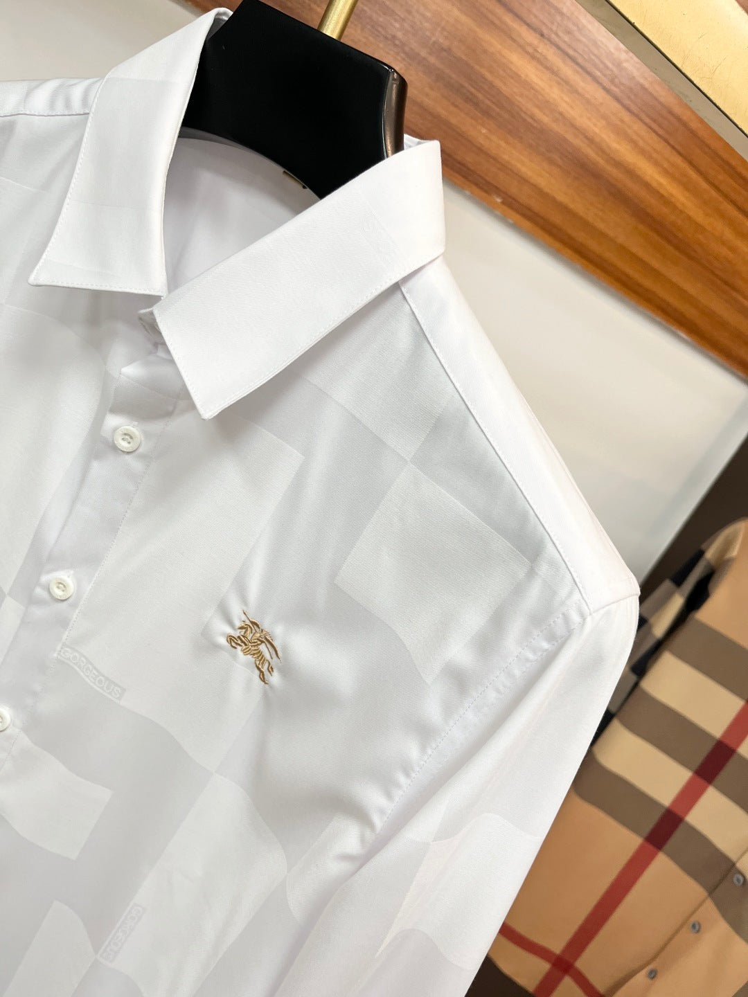 Burberry long-sleeve white shirt with wide collar, gold crest detail, and button cuffs