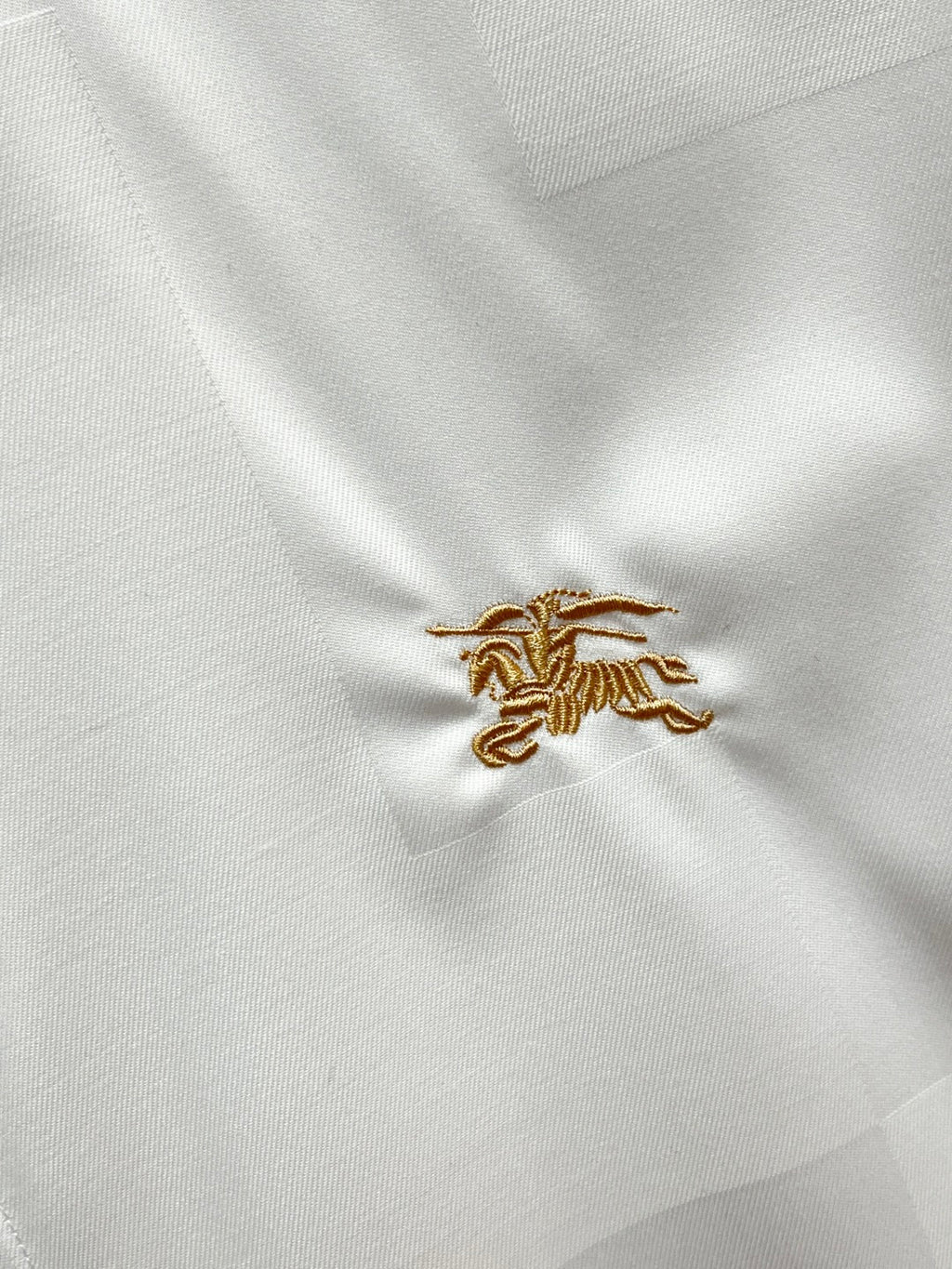 Burberry shirt embroidery: small gold crest on white fabric
