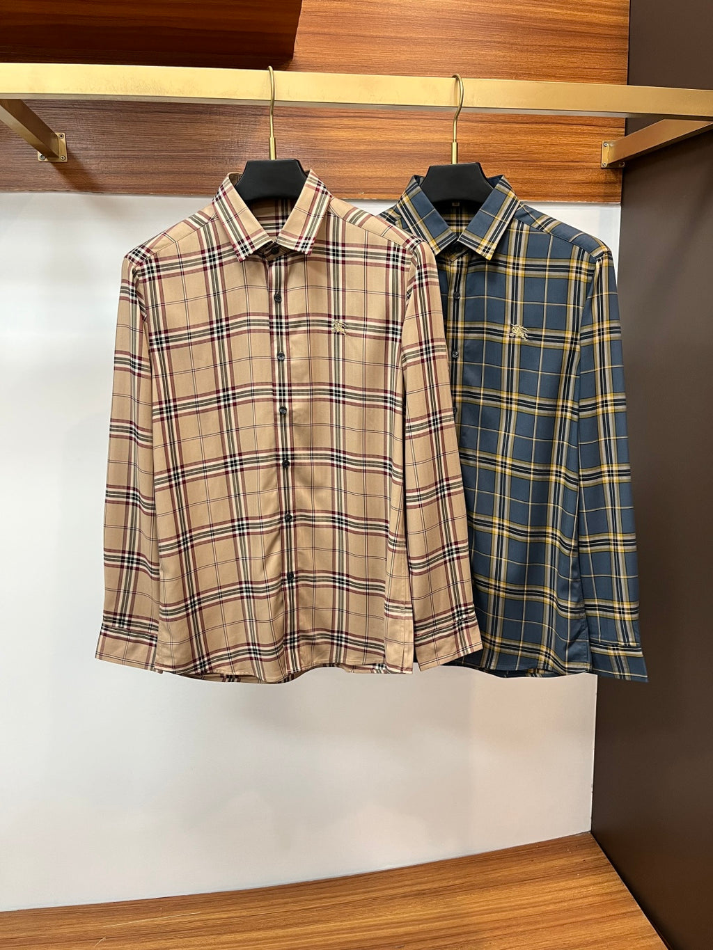 Two plaid button-up dress shirts on hangers: tan and blue colorways with collars