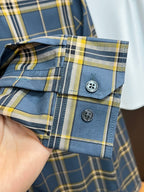 Buttoned cuffs and sleeve placket of blue plaid dress shirt with yellow accents