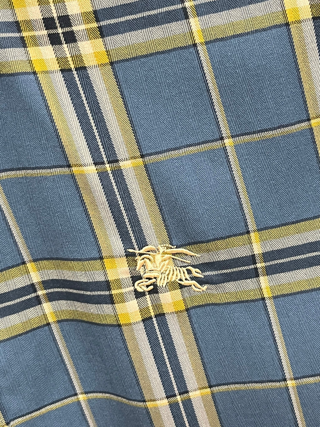 Plaid fabric close-up with blue, navy, white, and yellow grid lines
