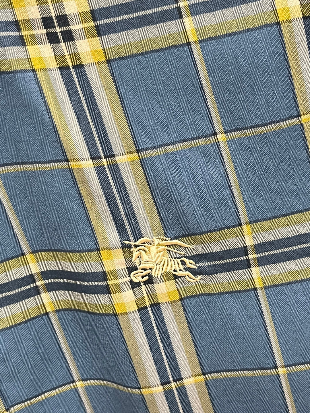 Plaid fabric close-up with blue, navy, white, and yellow grid lines