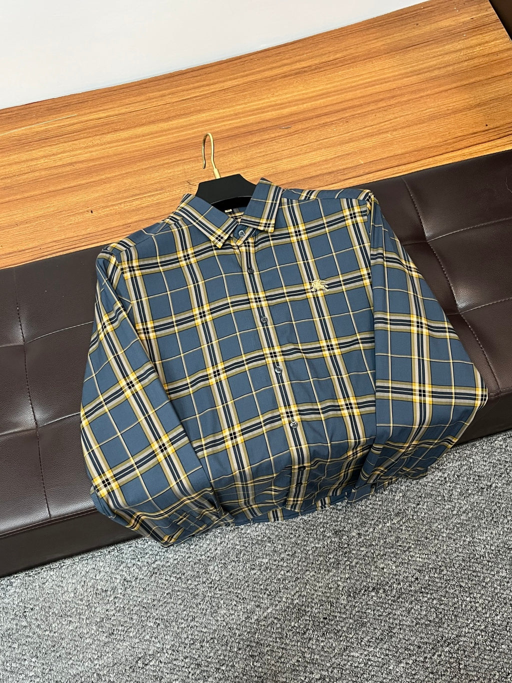 Folded blue and yellow plaid dress shirt on a hanger, long sleeves