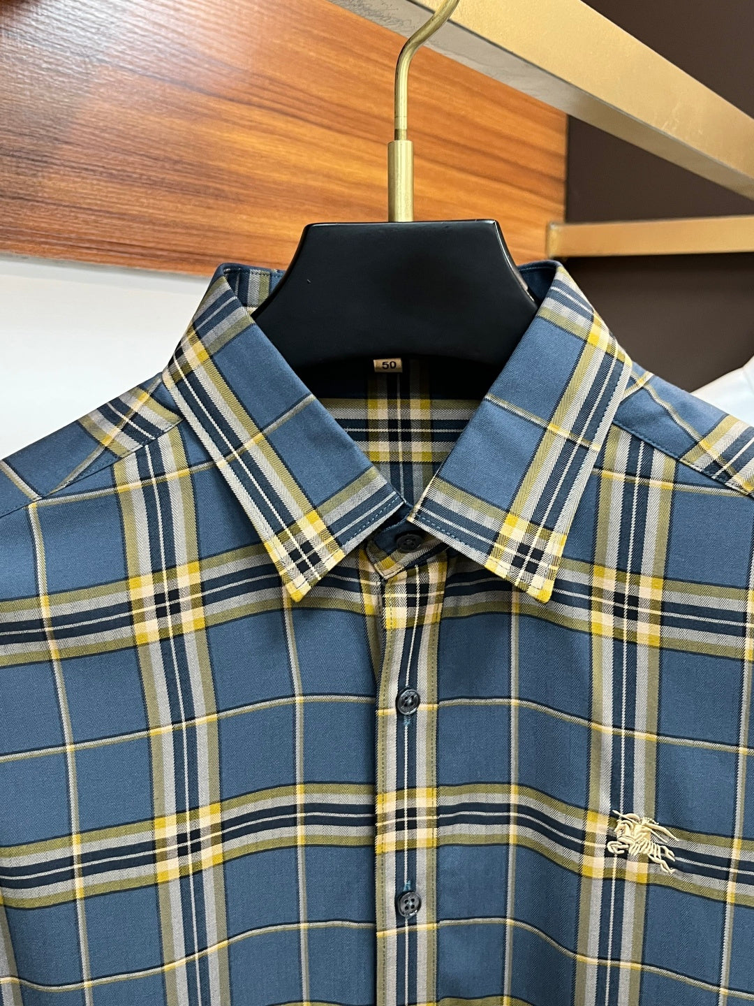 Plaid dress shirt collar and button placket detail in blue, yellow, and white