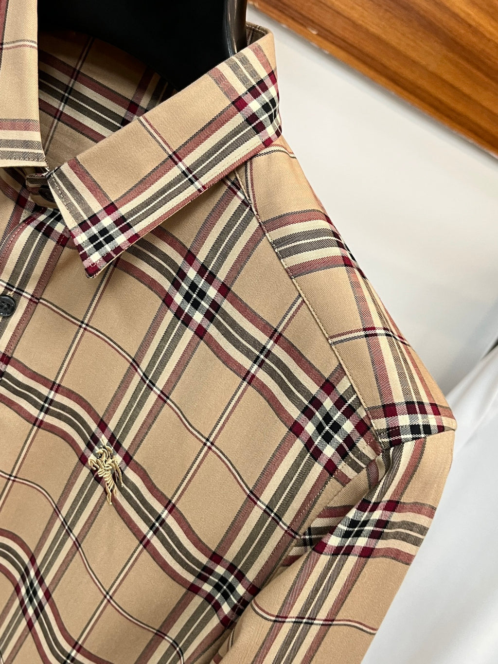 Beige plaid long-sleeve button-up shirt detail at shoulder and sleeve cuff