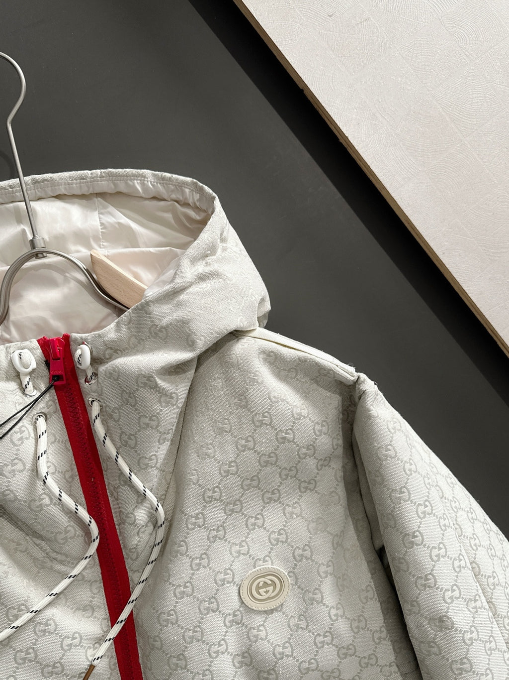 Gucci hooded jacket close-up, light-gray monogram, circular logo patch