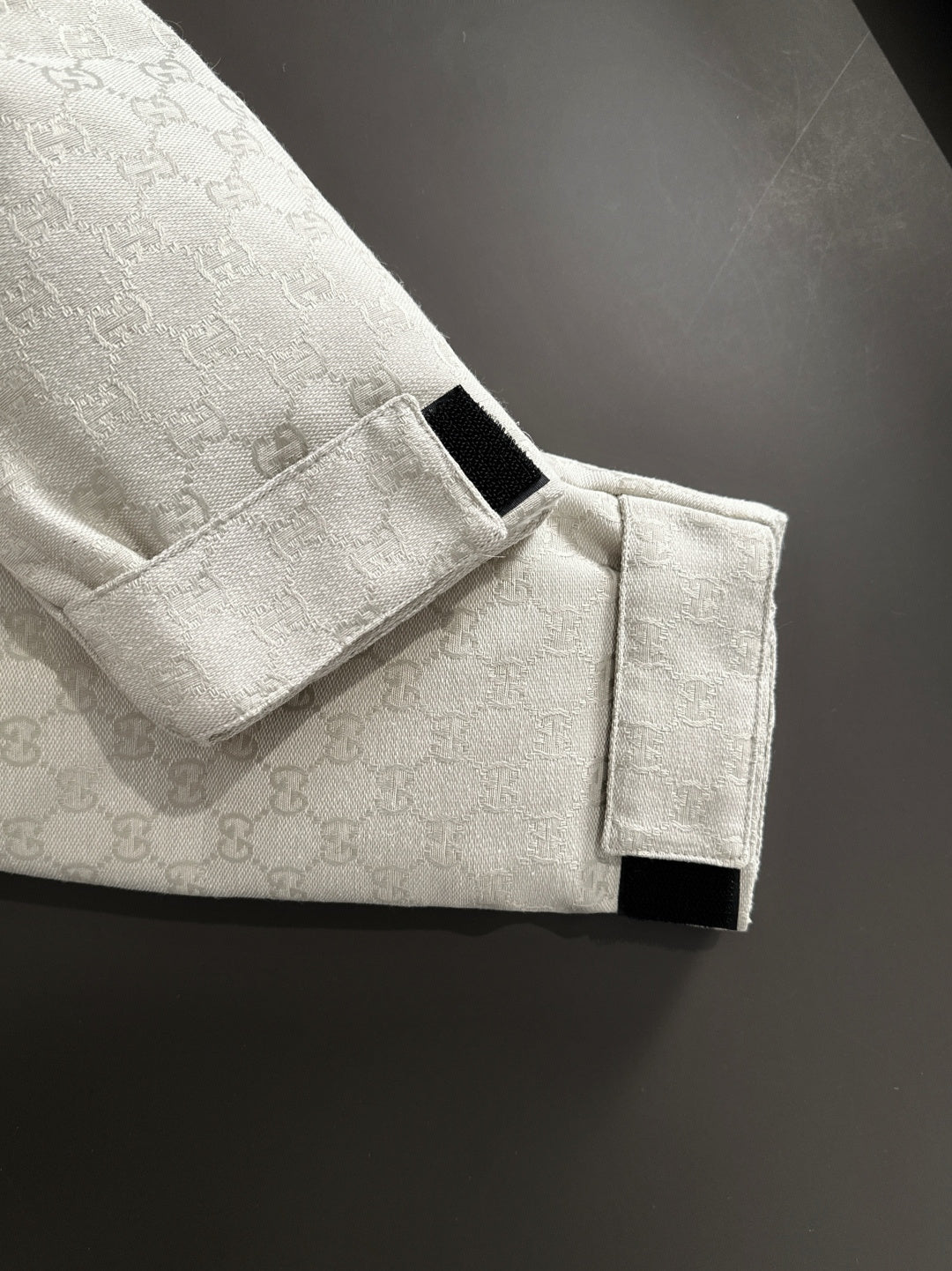 Gucci jacket button strap detail on light-gray monogram sleeve cuff