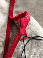 Gucci jacket zipper close-up, red zipper pull on light-gray monogram