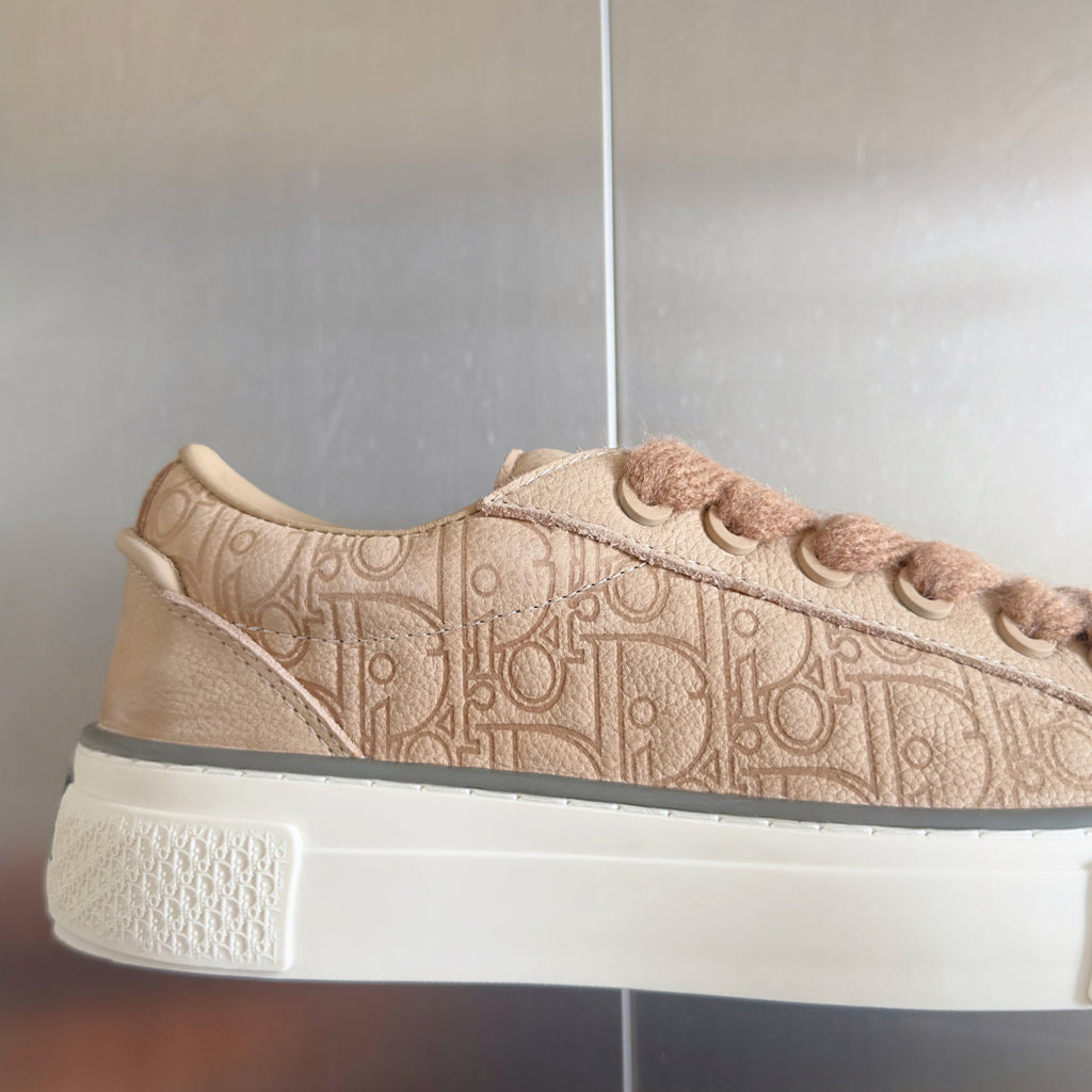 Dior unisex sneaker side view in beige with embossed monogram and lace eyelets
