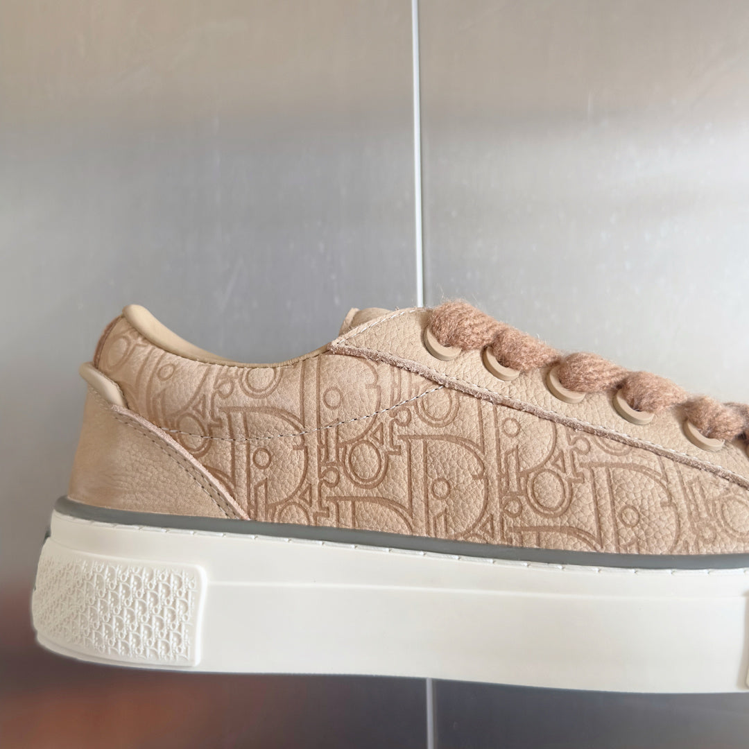 Dior unisex sneaker side view in beige with embossed monogram and lace eyelets