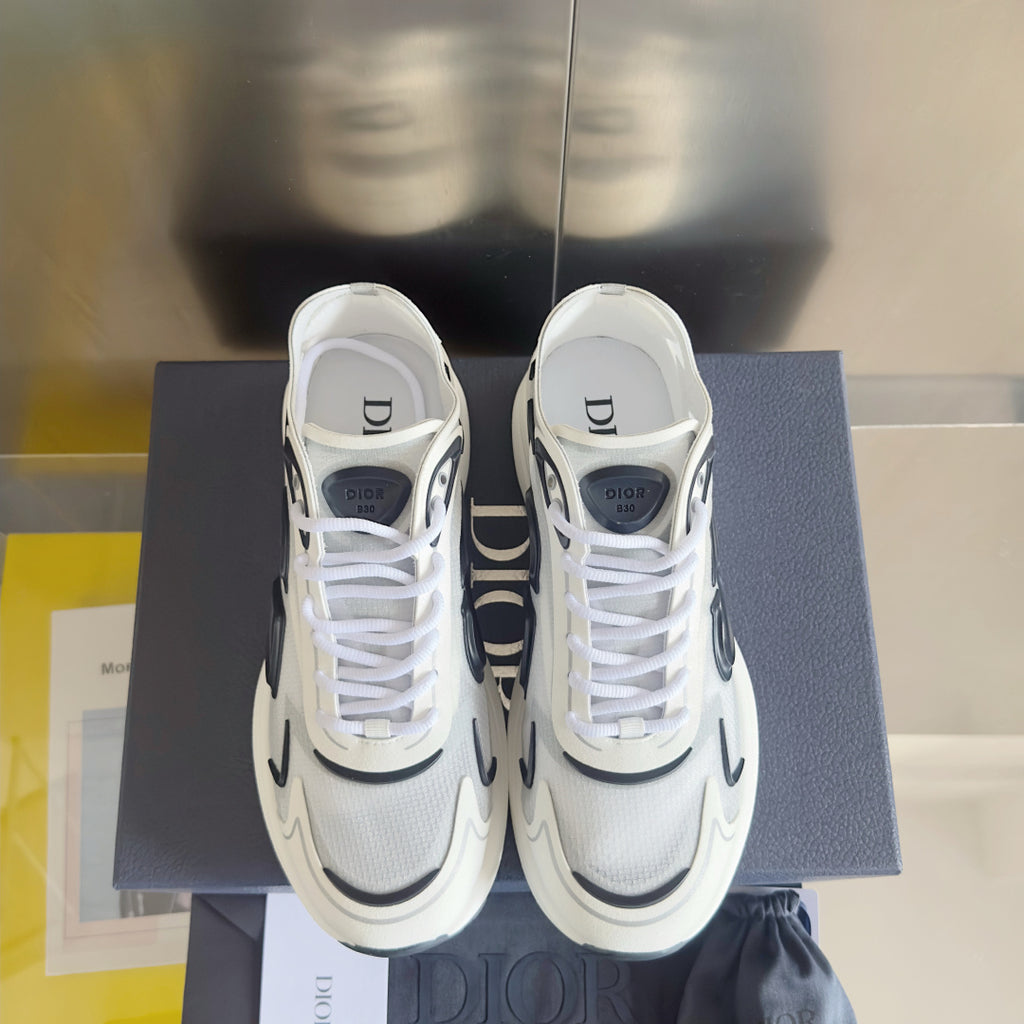 White unisex sneakers with black logo panels, lace-up closure, on a blue box.