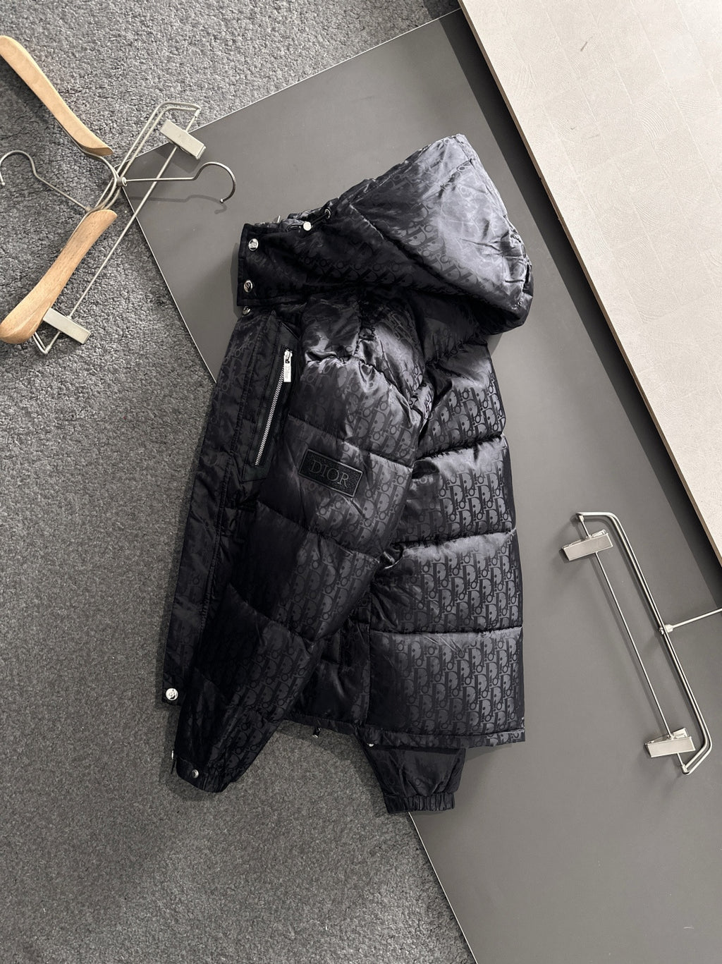 Long black puffer jacket with hood, front zipper, glossy quilted panels, snap placket