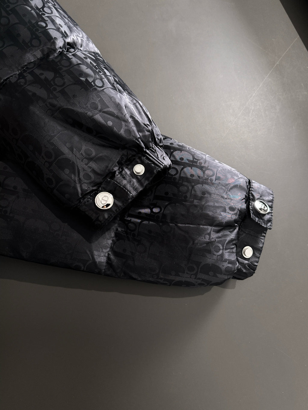 Black puffer jacket sleeve with snap cuff, Dior monogram fabric, button detail