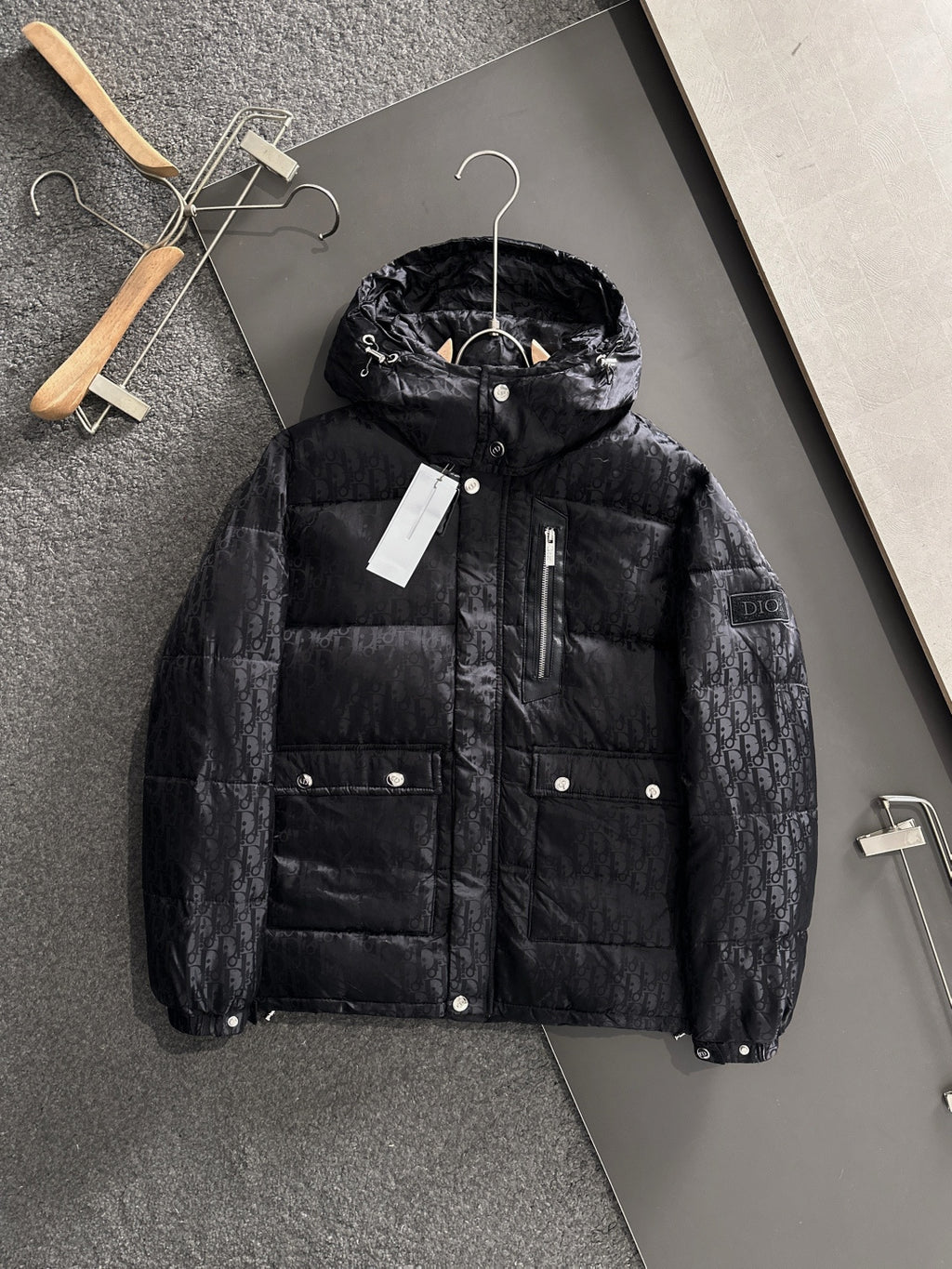 Long black puffer jacket with hood, front zipper, button pockets, Dior monogram