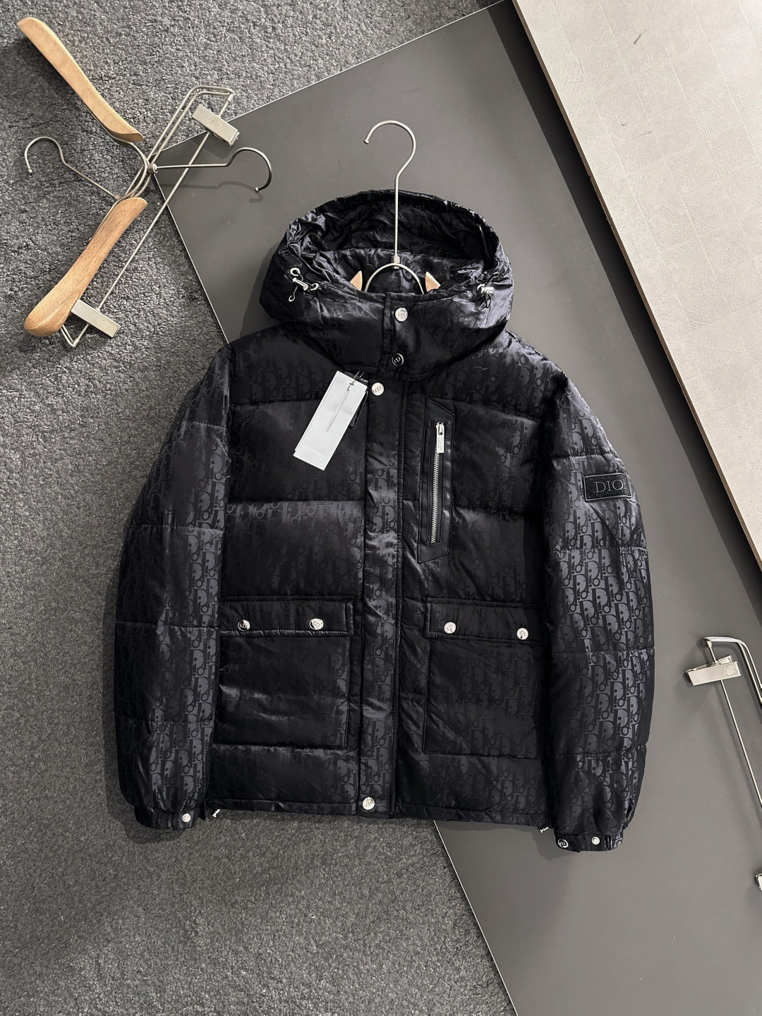 Long black puffer jacket with hood, front zipper, button pockets, Dior monogram